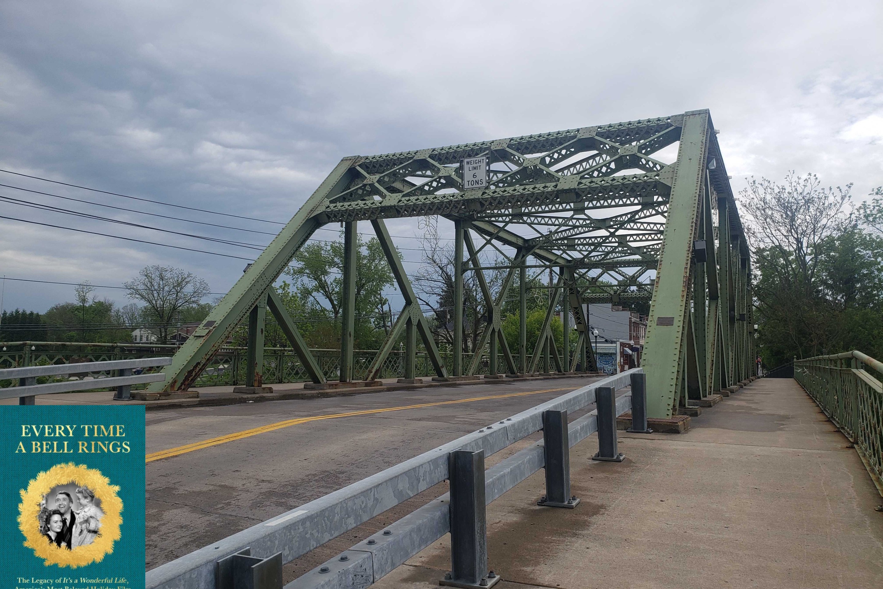 a small green bridge with a road for cars and a walking path