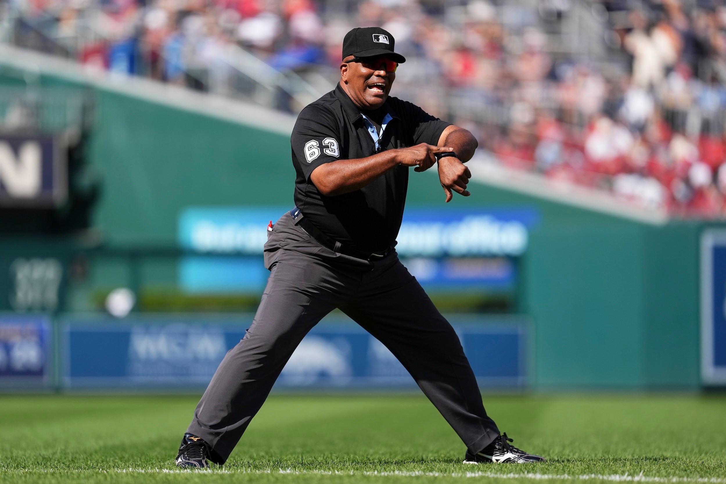 Laz Díaz gestures at his wrist and yells something during a baseball game.