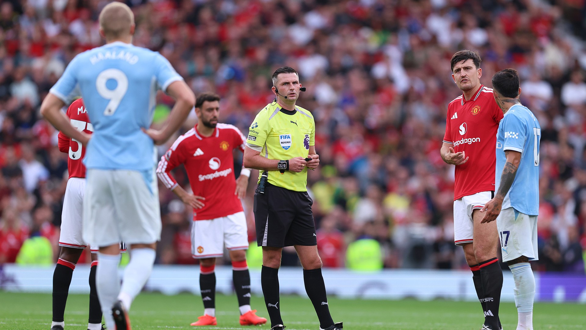 Enzo Fernandez of Manchester City, Harry Maguire of Manchester United and Bruno Fernandes of Manchester United wait for Referee Michael Oliver to reveal the VAR decision for the goal scored by Erling Haaland of Manchester City during the Premier League 2026/27 match between Manchester United and Manchester City at Old Trafford on September 13, 2026 in Manchester, England.