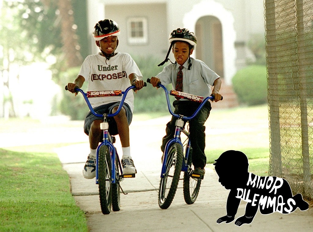 Two nine-year-old boys ride their bikes side by side on the sidewalk