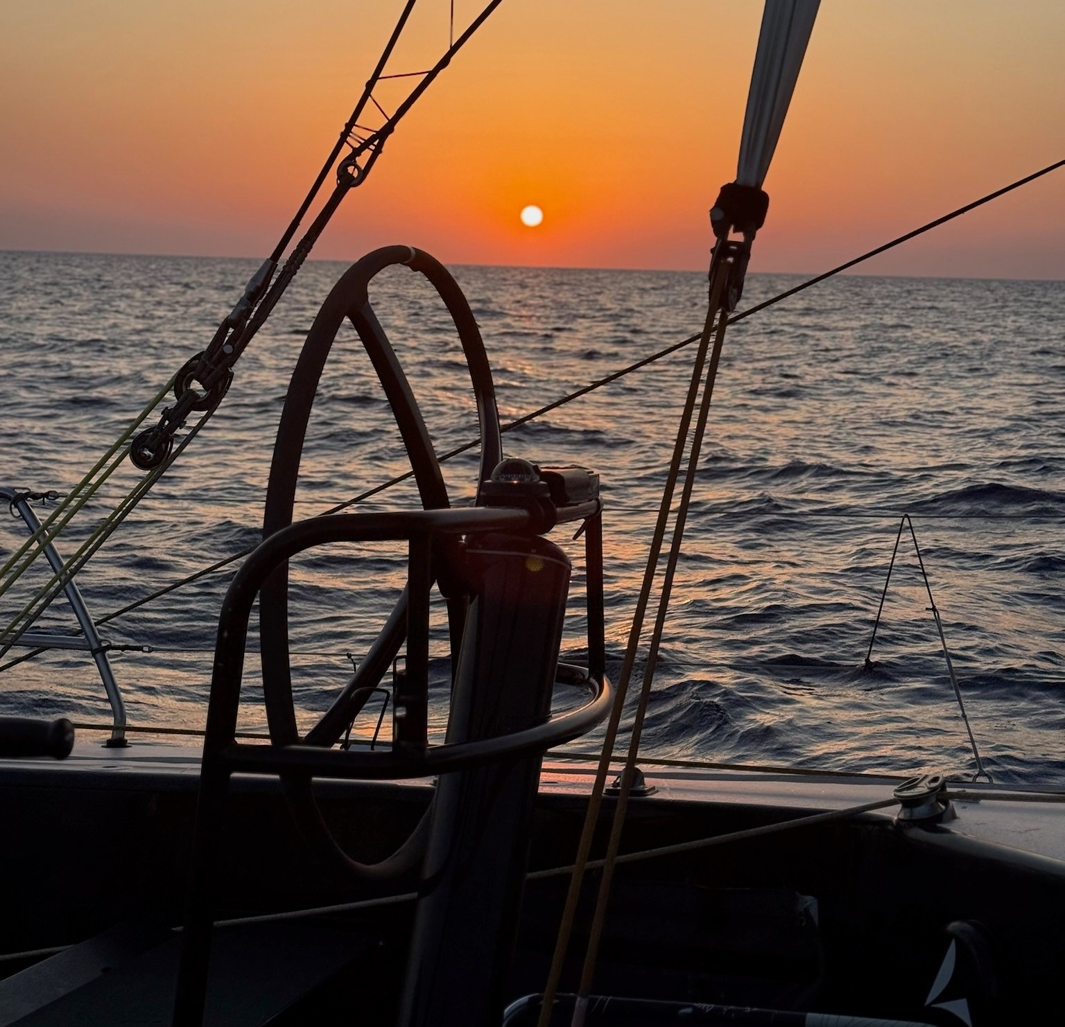 The sun setting behind a view of the boat's starboard helm, which is unoccupied.
