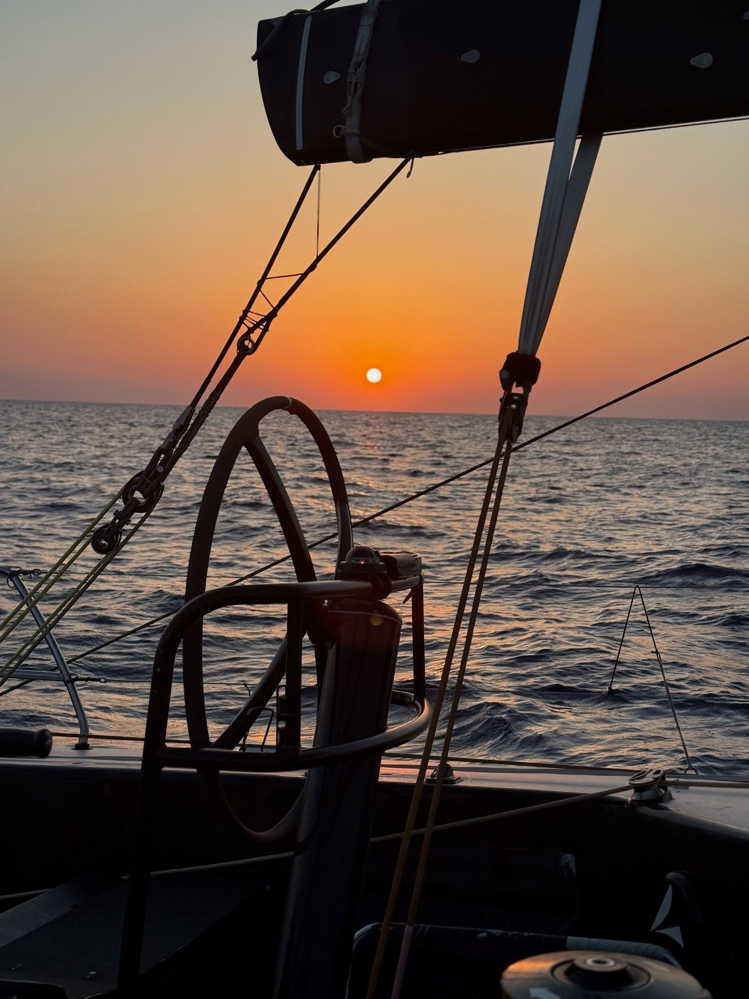 The sun setting behind a view of the boat's starboard helm, which is unoccupied.