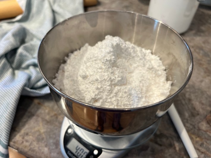 400 grams of icing sugar in a metal bowl on a food scale.