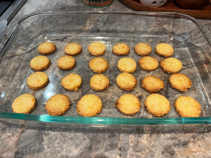 24 baked shortbread rounds, cooling in a glass baking dish.