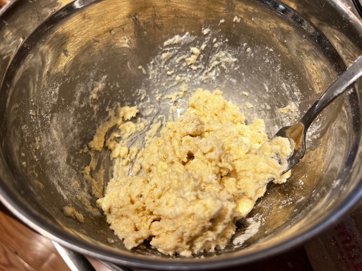 Lumpy, sticky biscuit dough, in a metal mixing bowl.