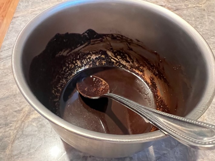 Fine coffee grinds and hot water, mixed in a metal bowl.