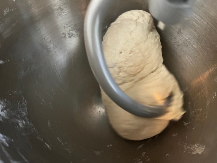 A blob of dough on a dough hook in a stand mixer
