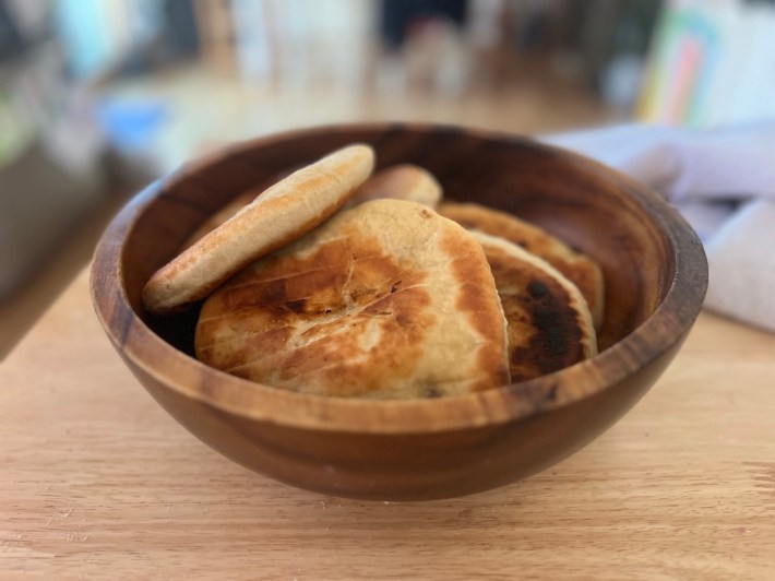 Fried flatbreads stacked in a wood bowl.