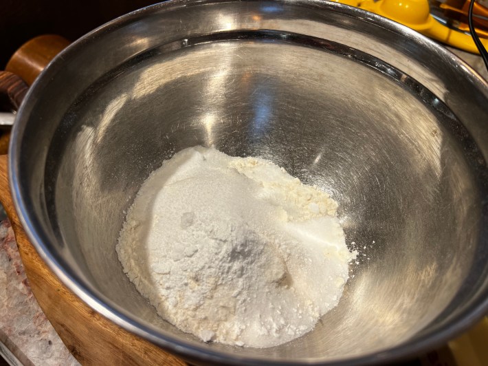 Flour, granulated sugar, and baking powder, in a metal mixing bowl.