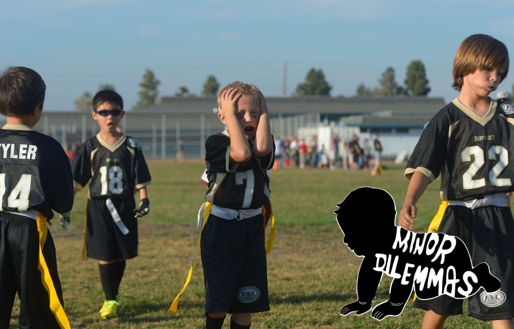 Young boys playing flag football react after fumbling the ball during a game.