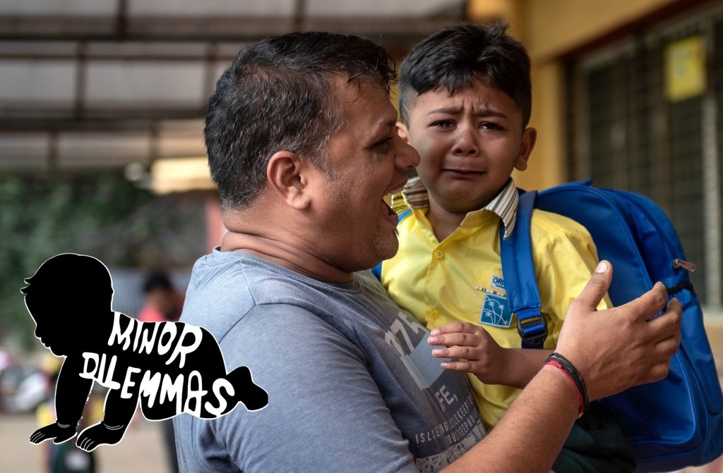 A father comforts his crying son on the first day of school in Mumbai