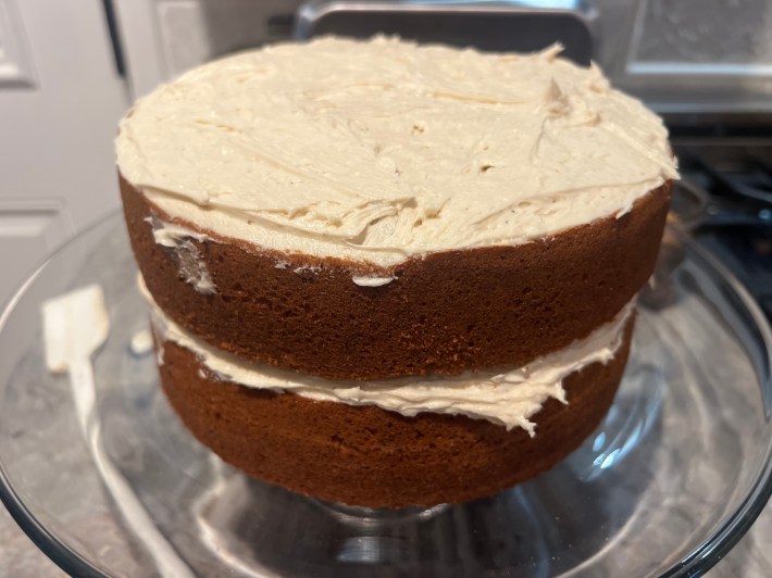Two sponges are stacked, with icing between them and on the top surface.
