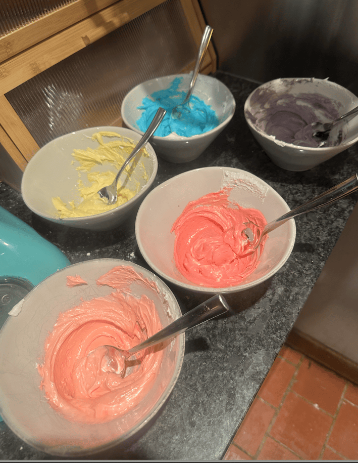 five different colored icings in bowls