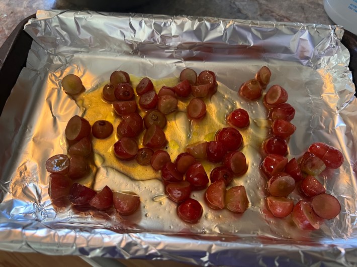 Sliced grapes with olive oil and honey in a baking dish.