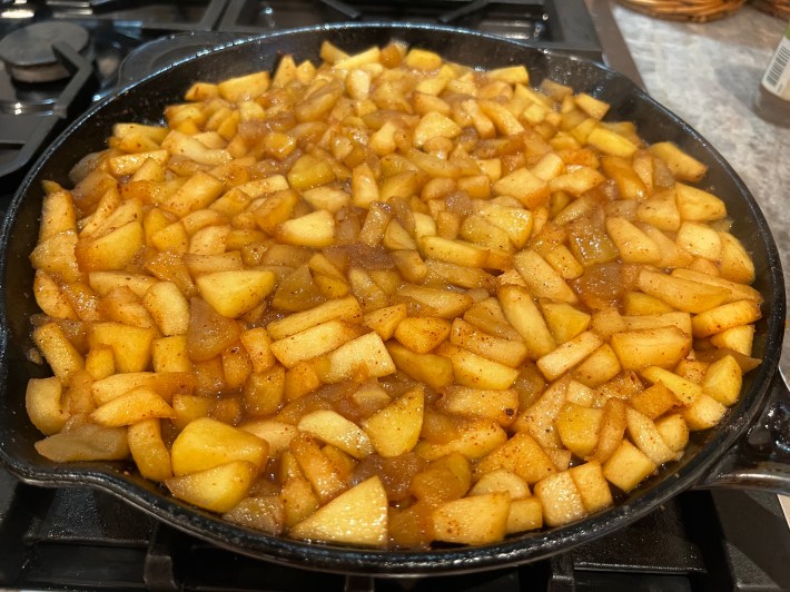 Softened apples cooking, leveled, in a cast iron skillet.