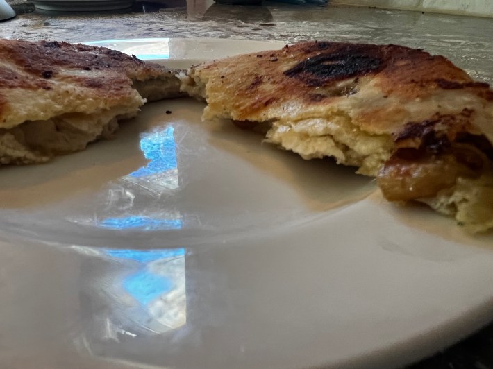 A fried flatbread is torn open.