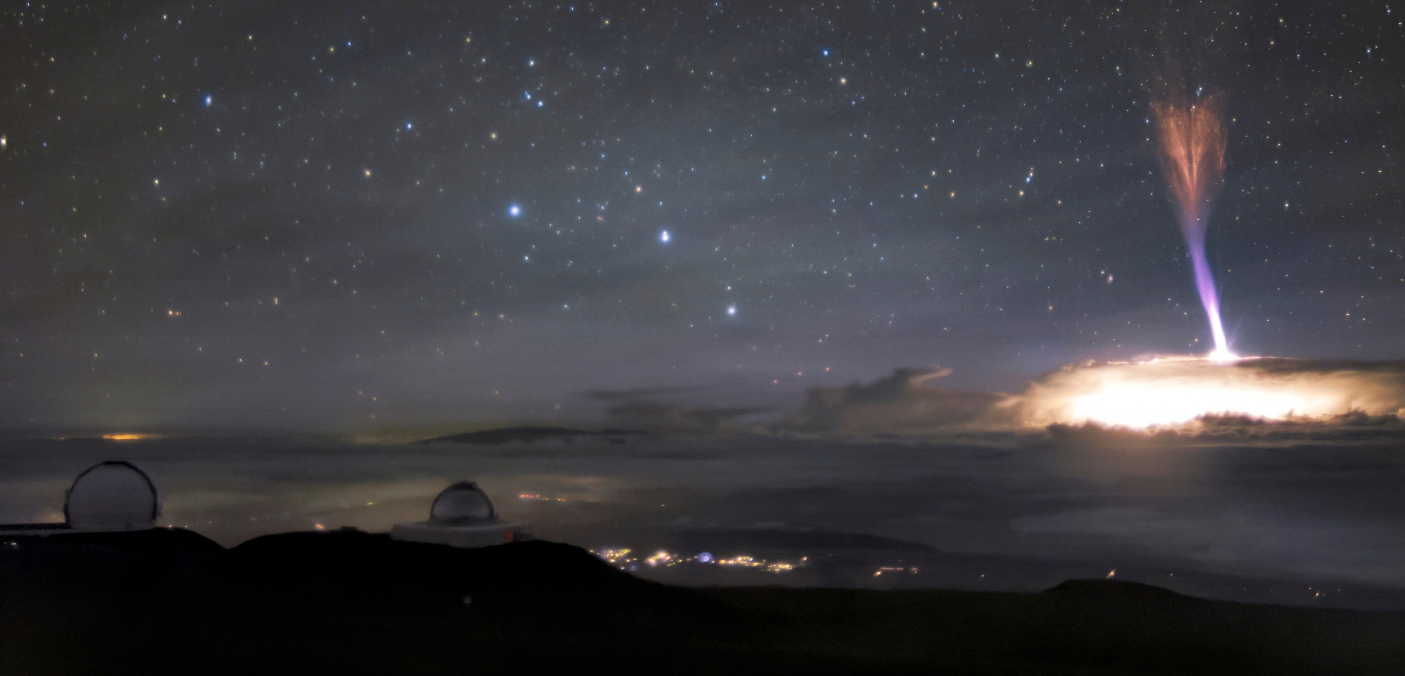 The telescopes at Maunakea sit calmly beneath a sky filled with extraordinary light. Amongst these telescopes is Gemini North, the northern member of the international Gemini Observatory, a Program of NSF NOIRLab. Gemini North sits at an altitude of around 4200 meters (13,800 feet). Not only does this altitude facilitate world-class astronomical observations, but Gemini North’s nighttime Cloudcams were able to capture the extraordinary light phenomena seen on the right side of the image. The column of blue and red lights surrounded by a bright blaze of white light appears so otherworldly that it looks like it must be a special effect. This breathtaking image, however, is entirely real. It features the lightning phenomena named a red sprite. Red sprites are distinctive because of their color, and also the direction in which they strike. The red and blue lights are shooting down from 50-90 kilometers toward the top of the cloud deck. It is extremely rare to capture these phenomena on camera and even more so from this unique perspective. This image was taken on 24 July 2017.