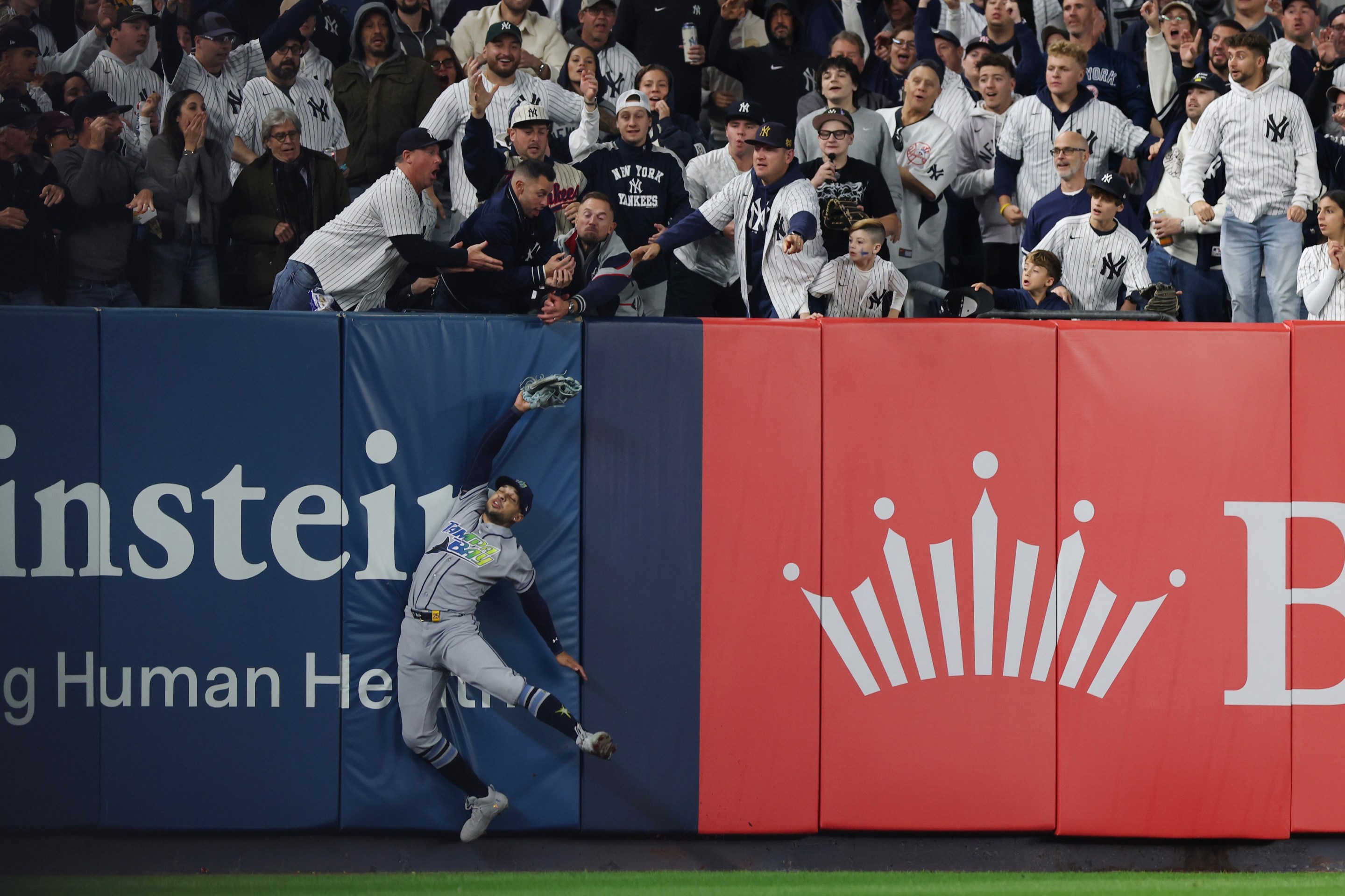 Victor Mesa Jr. #25 of the Tampa Bay Rays is unable to make a catch as fans interfere on a ball hit by Anthony Volpe #11 of the New York Yankees.